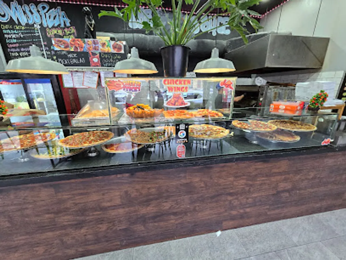 Customers enjoying freshly baked pizza at The Swiss Slice in Brooklyn